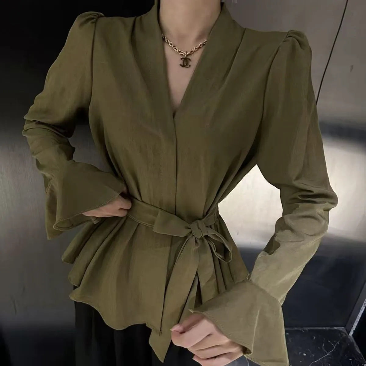 Women's black French-style shirt with an irregular collar and long bell sleeves laid flat.