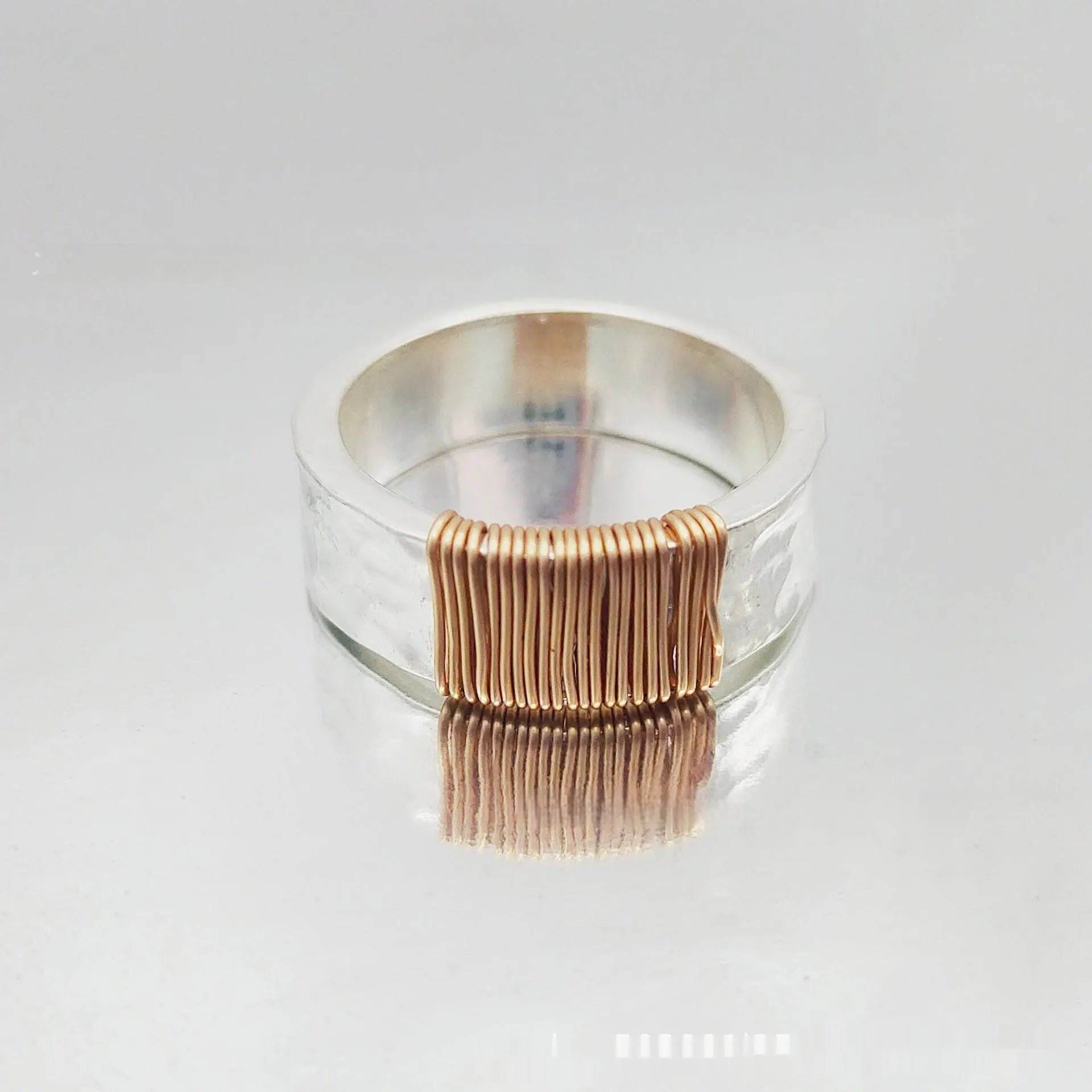 Silver golden geometric coil copper ring for men and women on a grey background.