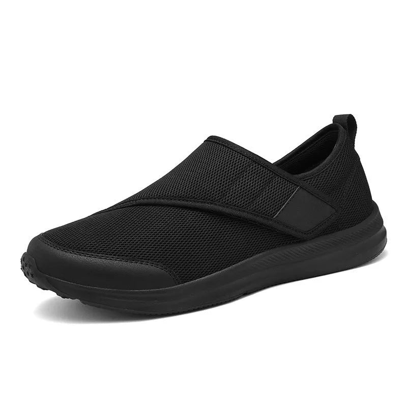 A pair of grey Velcro walking shoes with a mesh upper and round toe, shown on a white background.