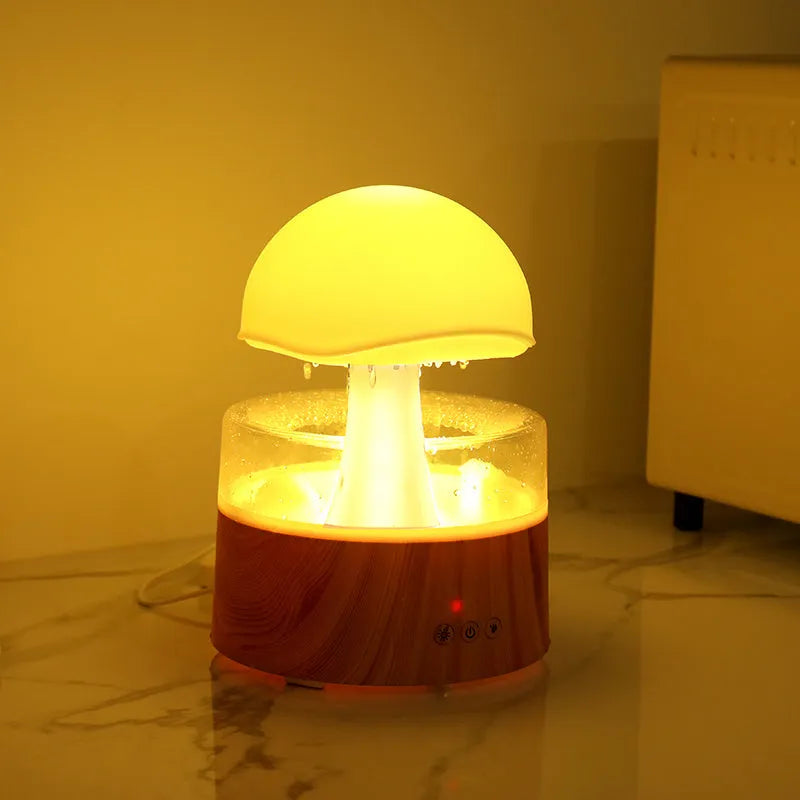 White rain cloud shaped ultrasonic humidifier and aromatherapy diffuser with coloured lights on a wooden table.