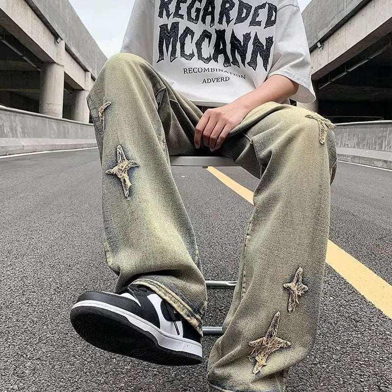 Men's loose denim trousers in black, straight-leg style with zipper fly, lying flat on a surface