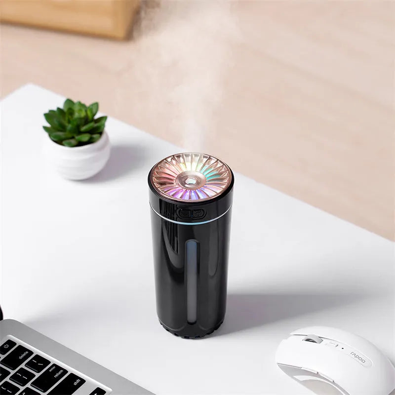 Compact black wireless USB humidifier with colourful LED lights on a car cup holder.
