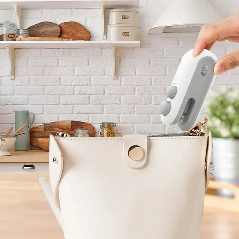 White handheld vacuum sealing machine with magnetic back and cutter blade for chip bags