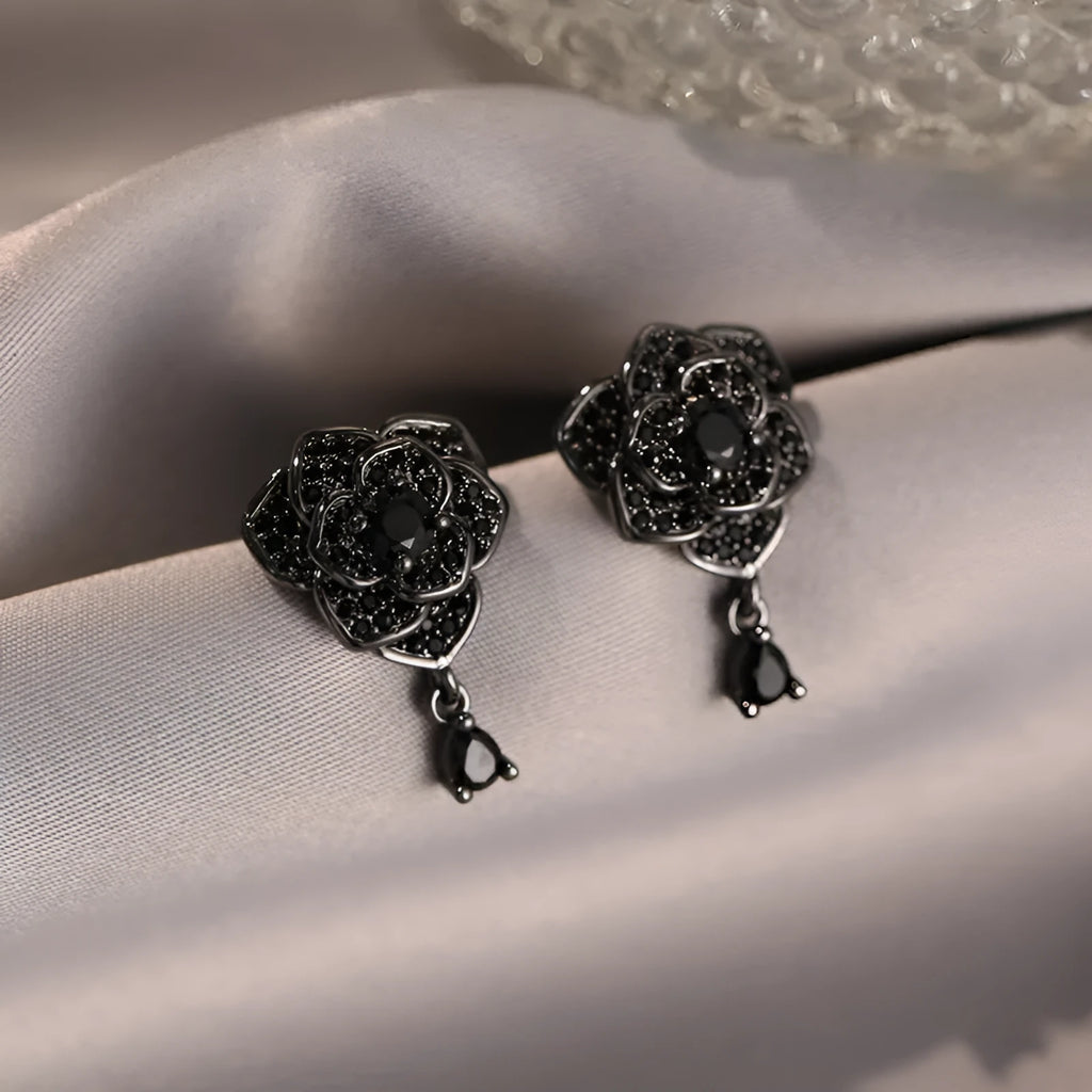 Close-up of women's black rose zircon flower stud earrings with 18K gold plating.