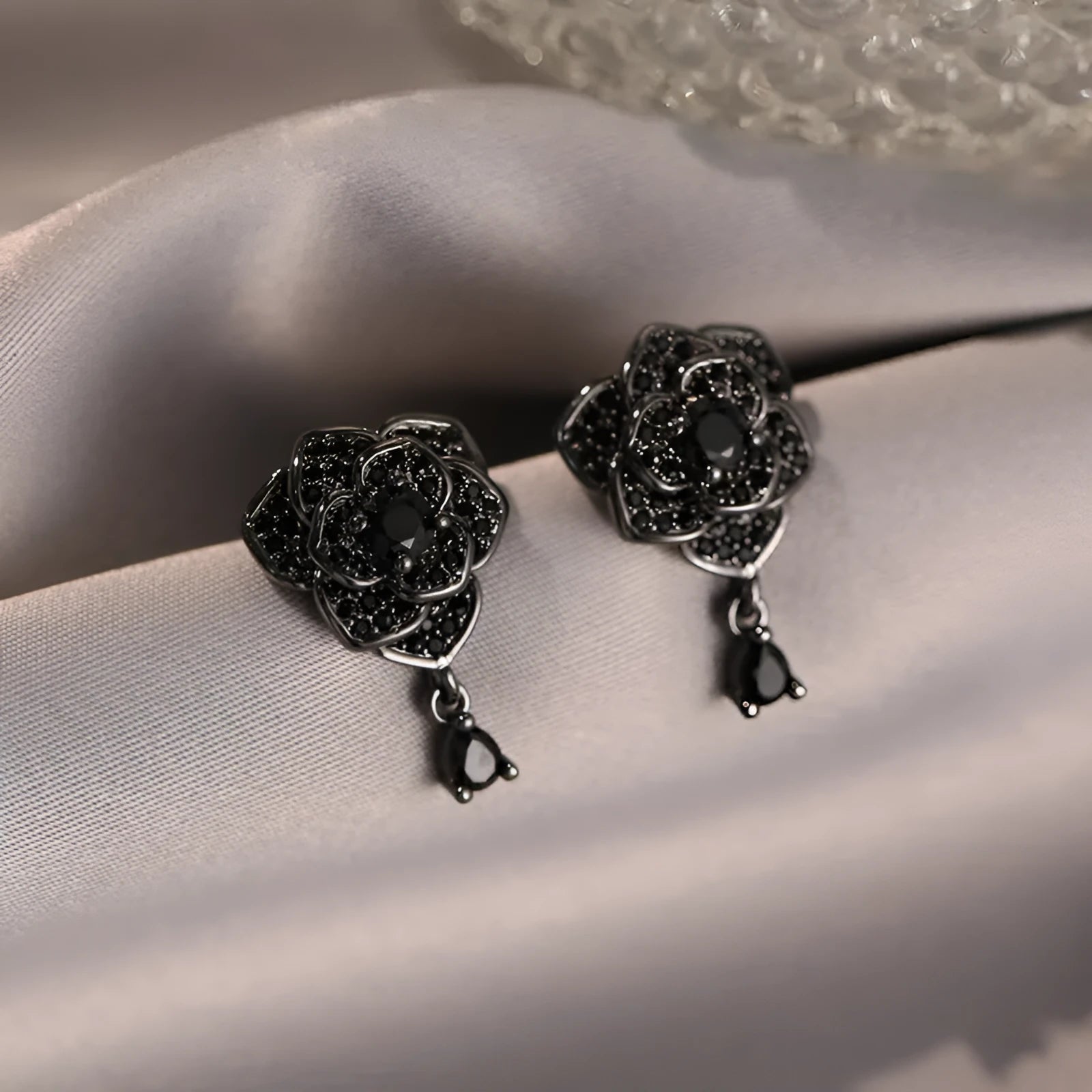 Close-up of women's black rose zircon flower stud earrings with 18K gold plating.