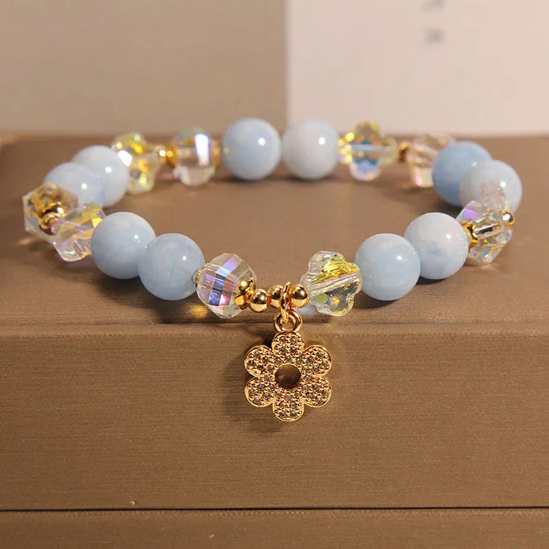 Women's aquamarine crystal bracelet with a four-leaf clover charm and small pearl accent.