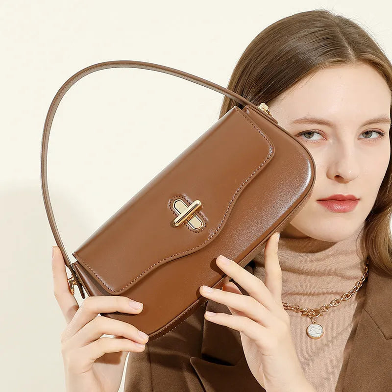 Genuine leather baguette handbag in black with clamshell opening showing internal phone and document pockets