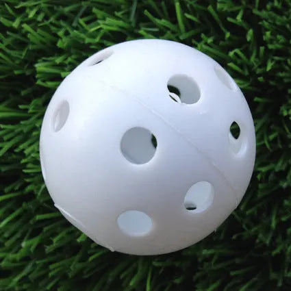 Hollow plastic golf practice ball in orange colour on indoor surface
