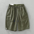 Men's loose straight fit linen shorts in green with drawstring waist, shown laid flat