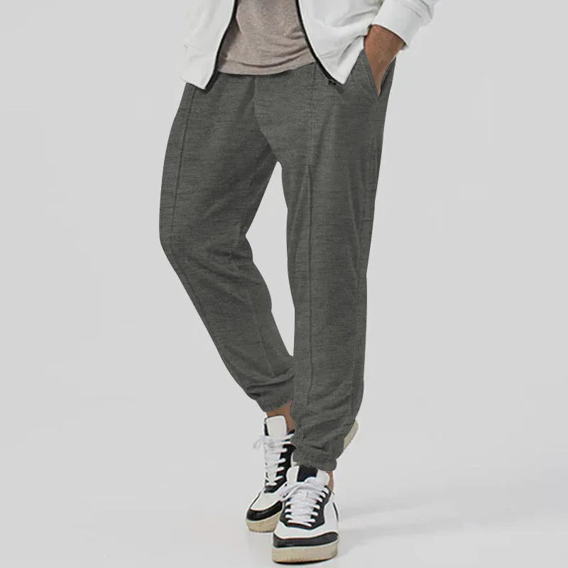 Men's grey cotton blend track sweatpants with a loose tapered fit and straight leg on a mannequin.