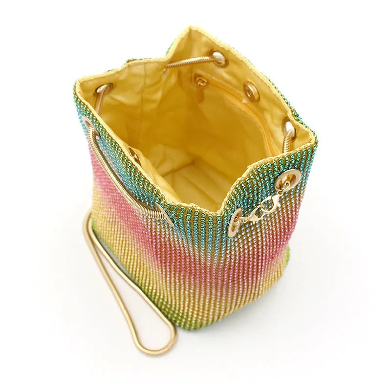 Sparkling rhinestone bucket bag with drawstring closure on a soft texture.
