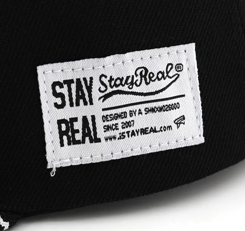 Black and white cotton baseball cap with letter embroidery on the front, showing adjustable strap at back.