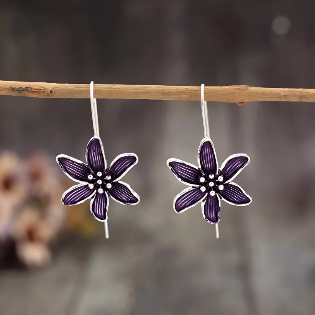 A pair of retro-style purple flower-shaped alloy earrings for women on a plain background.