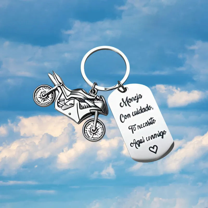 Stainless steel motivational motorcycle keychain with flannel storage pouch on a grey background.