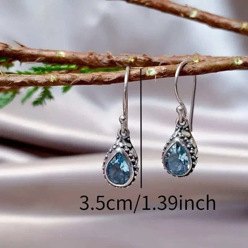 Retro style drop-shaped blue gem inlaid earrings in silver alloy, unisex jewellery on display