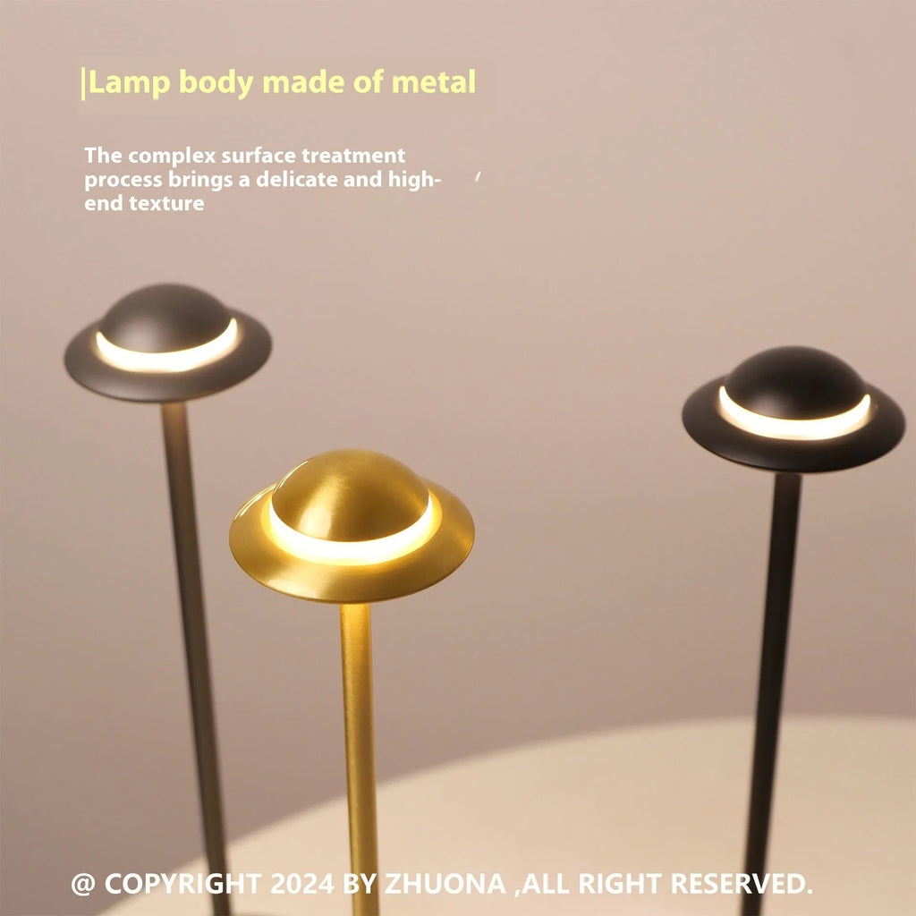 Metallic UFO-shaped rechargeable table lamp with touch controls in black finish on a wooden desk.