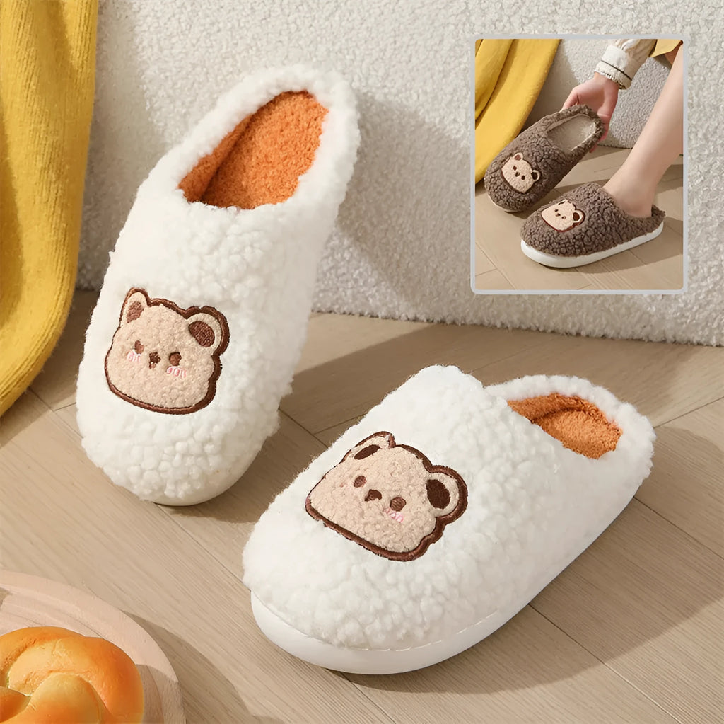 Pair of cute cartoon bear winter slippers with plush upper and non-slip TPR sole on a bedroom floor