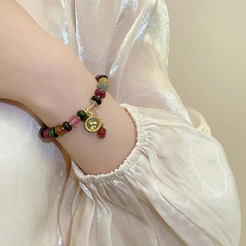 Colourful tourmaline beaded bracelet with geometric abacus beads and a rabbit pendant on a white background.