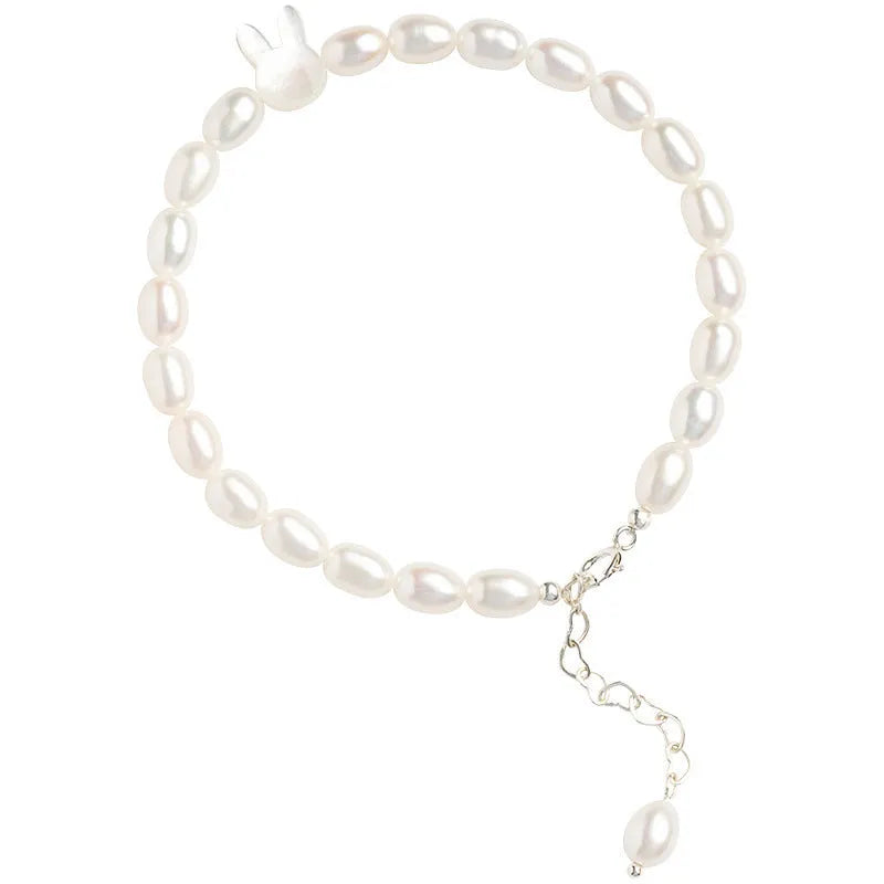 White pearl and 925 silver rabbit charm bracelet on a model's wrist, showing adjustable elastic string.