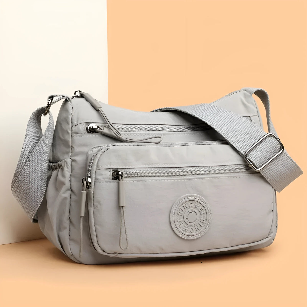 Grey water-repellent nylon crossbody bag showing three-dimensional pockets and a single shoulder strap.