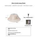 Beige wine bottle shaped camping lantern with USB-C port on a wooden table.