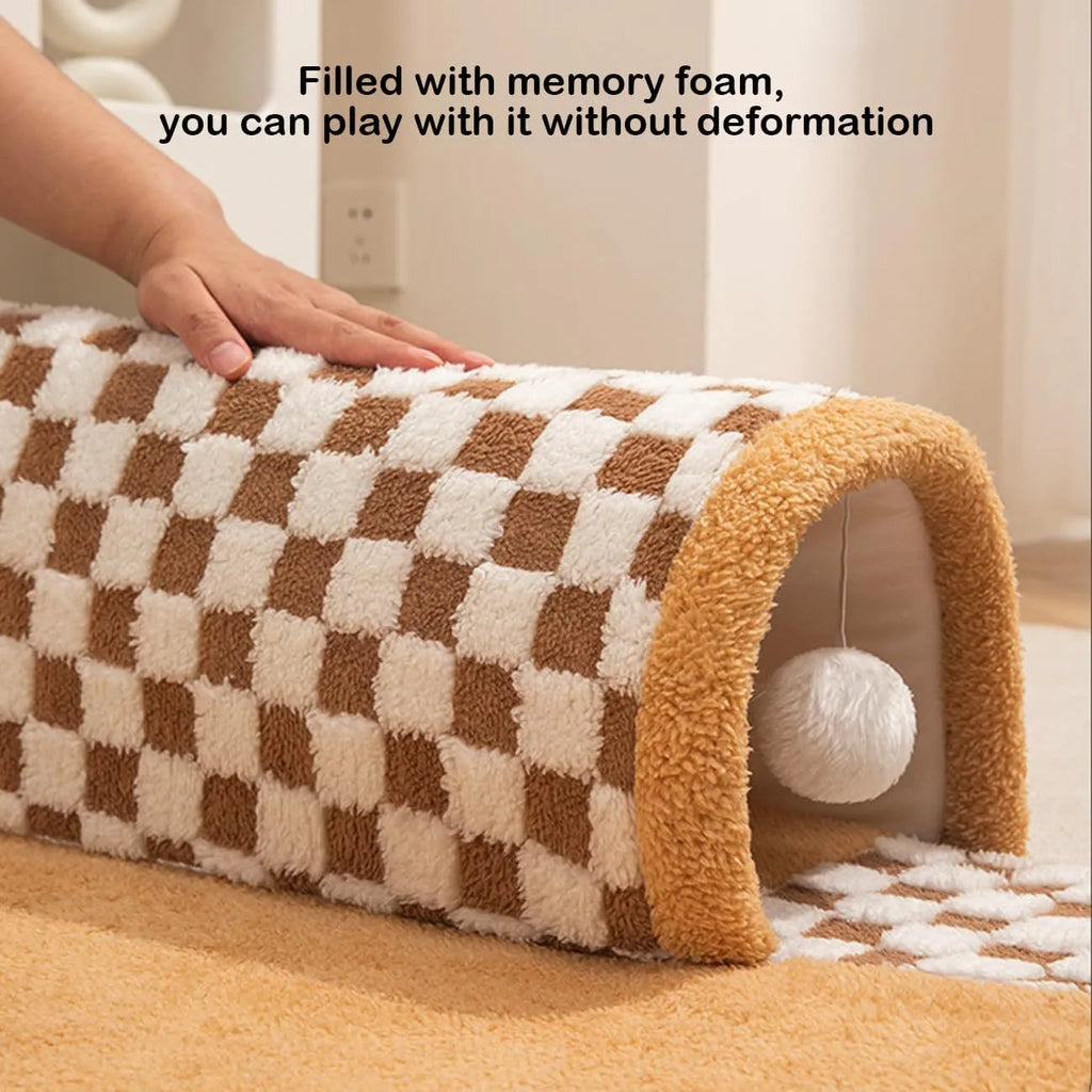 Large plush fan-shaped dog and cat bed with central tunnel, in coffee colour, on a floor.