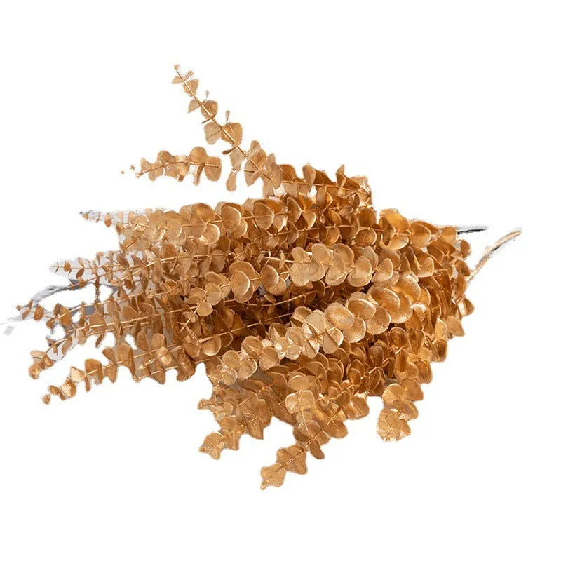 Gold plastic artificial flower arrangement featuring Persian eucalyptus and ginkgo leaves with single rose and peacock feathers