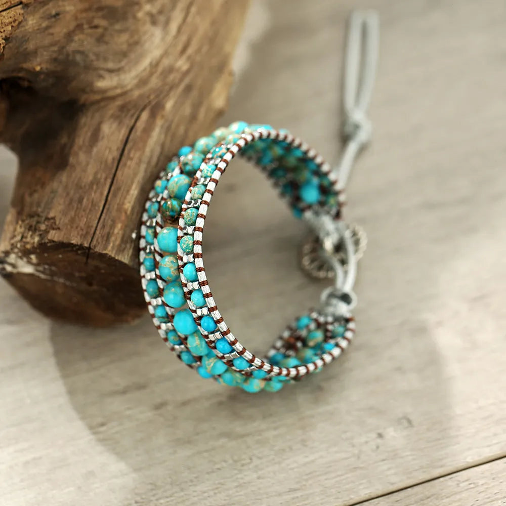 Handmade turquoise geometric inlaid gem bracelet in green with starry sky meteor shower pattern on a white background.