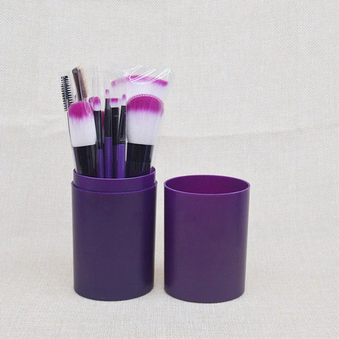 12 makeup brushes with pink handles and black bristles arranged in white storage bucket