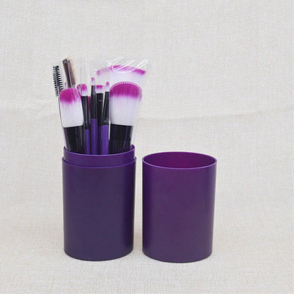 12 makeup brushes with pink handles and black bristles arranged in white storage bucket