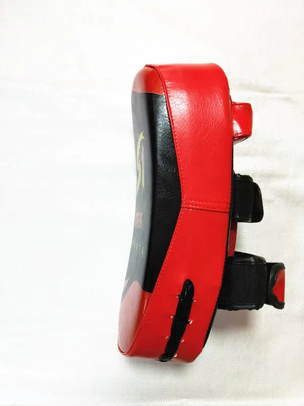 Black and red square martial arts training pad held in hand, showing double buckle strap.