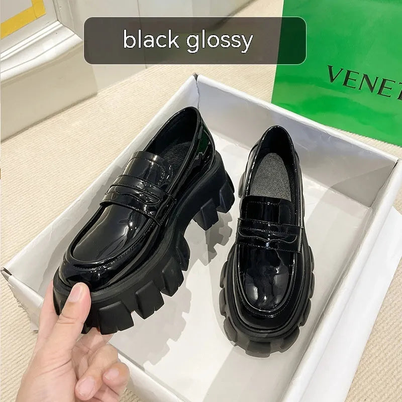 A pair of British style wide fit loafers in patent leather with a rubber sole.