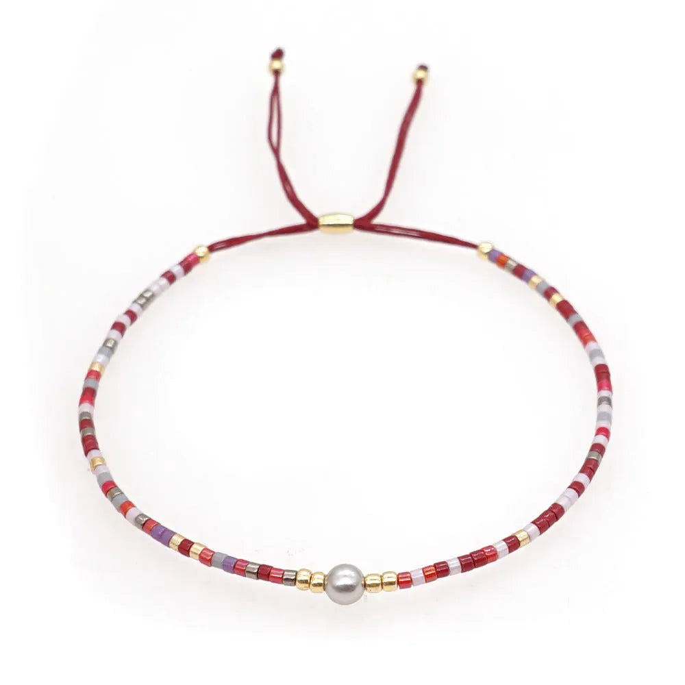 Handmade bohemian style bracelet with geometric semi-precious stone and colourful glass beads on a wrist.