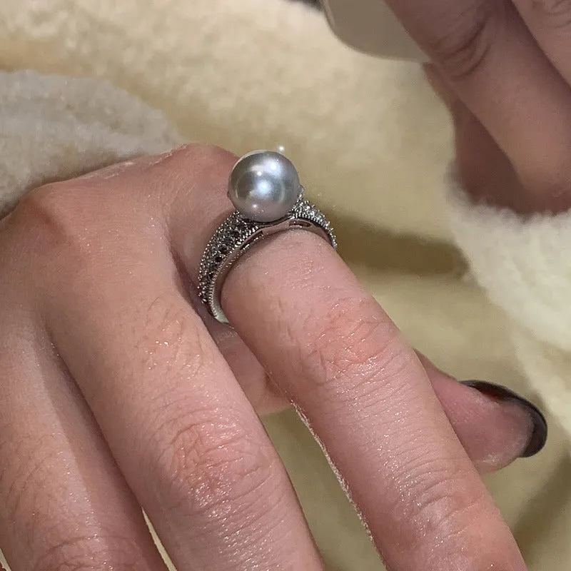 Adjustable open copper ring with geometric shape and black pearl detail on index finger