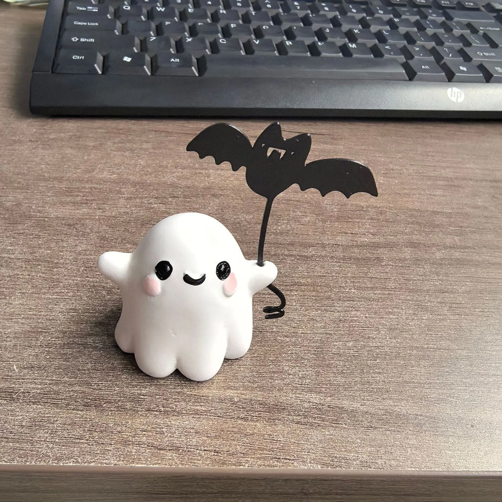 Small resin statue of a ghost walking a dog, a Halloween decoration.