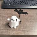 Small resin statue of a ghost walking a dog, a Halloween decoration.