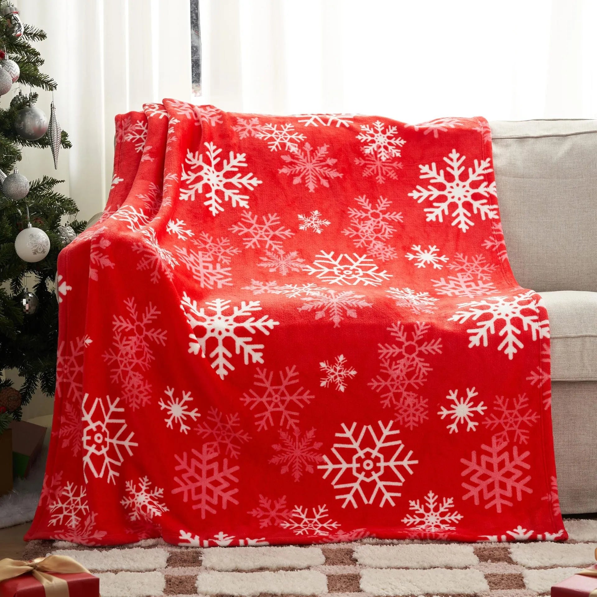 Reversible soft flannel Christmas blanket in a selection of colours and sizes on a sofa.