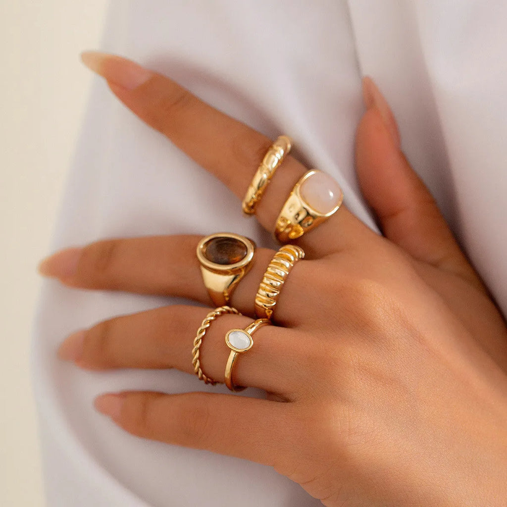 Six light gold irregular alloy rings with geometric shapes on a light background