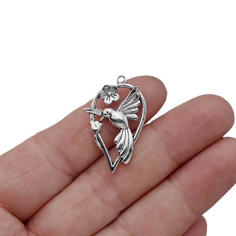 Close-up of a silver-toned alloy magpie bird pendant charm with electroplated finish, shown from the front.