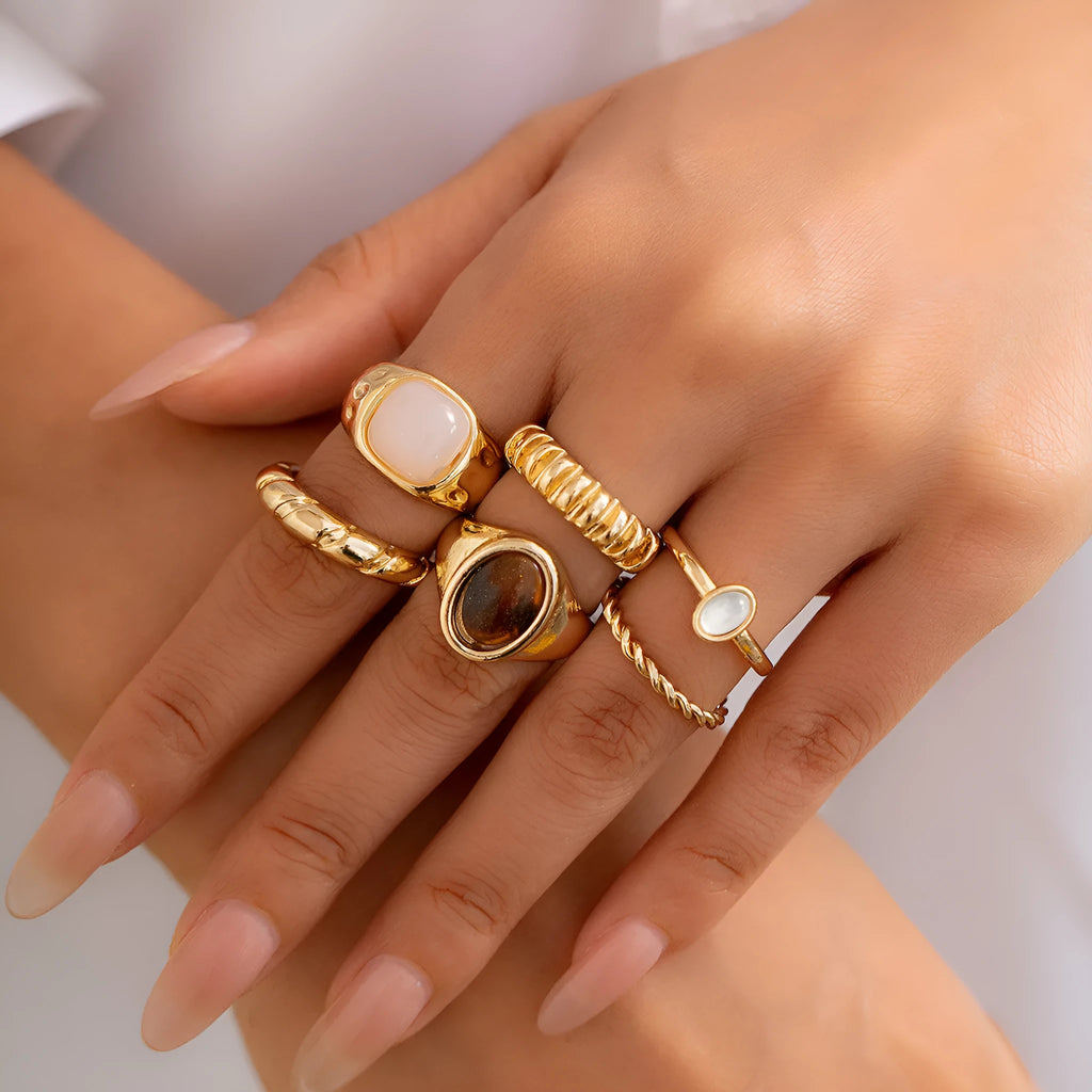 Six light gold irregular alloy rings with geometric shapes on a light background