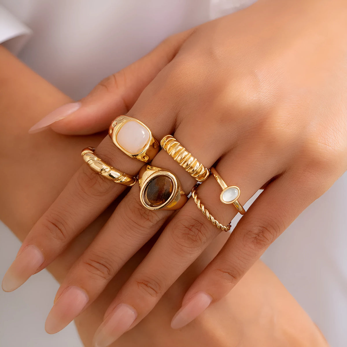 Six light gold irregular alloy rings with geometric shapes on a light background
