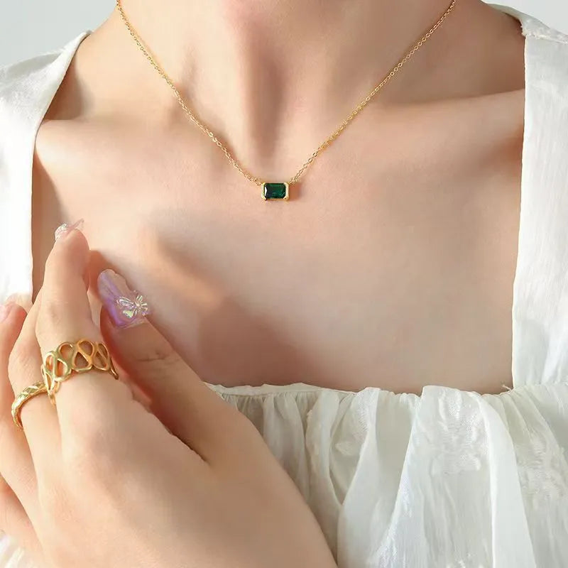 Gold geometric quadrilateral pendant necklace with inlaid cubic zirconia stones on a chain.