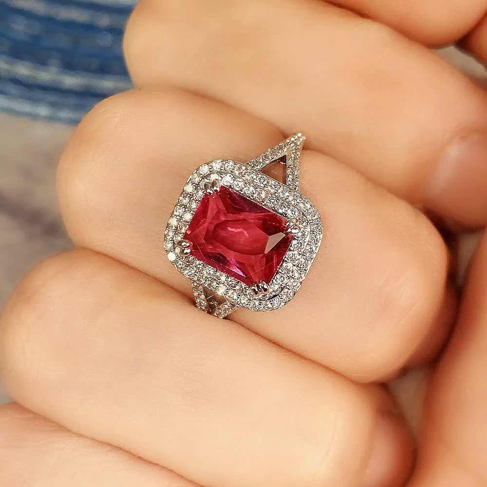 Women's copper square geometric ring with red rhinestones on a finger.