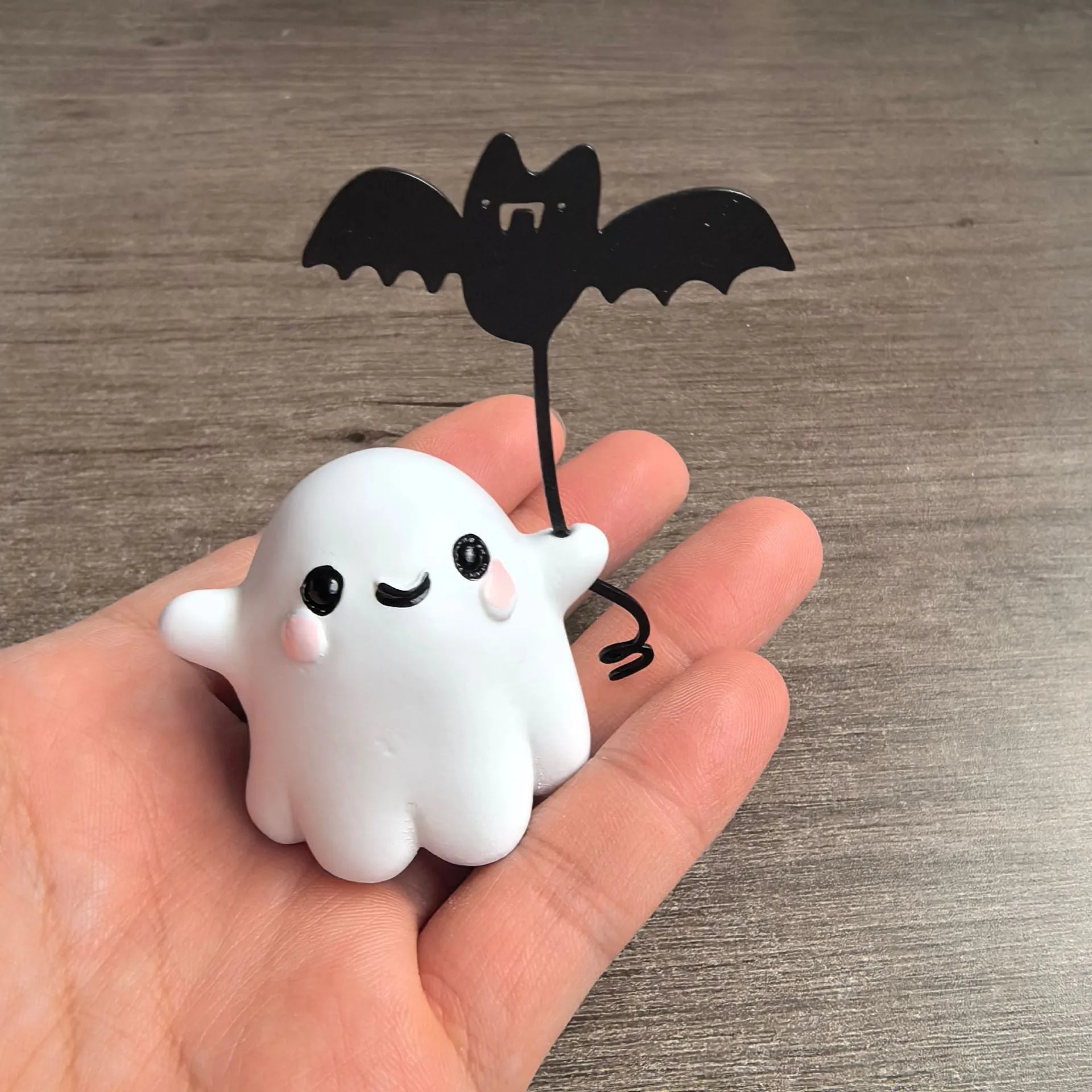 Small resin statue of a ghost walking a dog, a Halloween decoration.