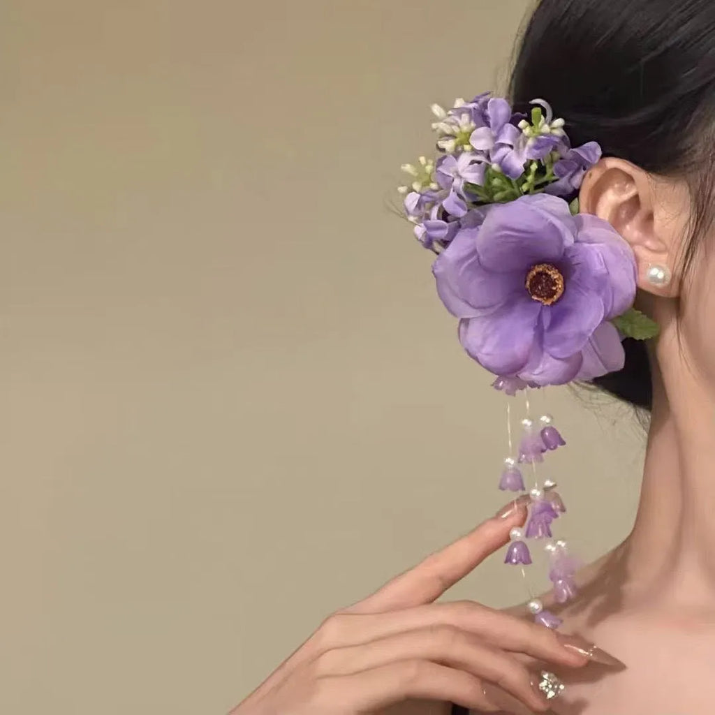 Women's floral tassel side clip hair accessory in purple or yellow on white background.
