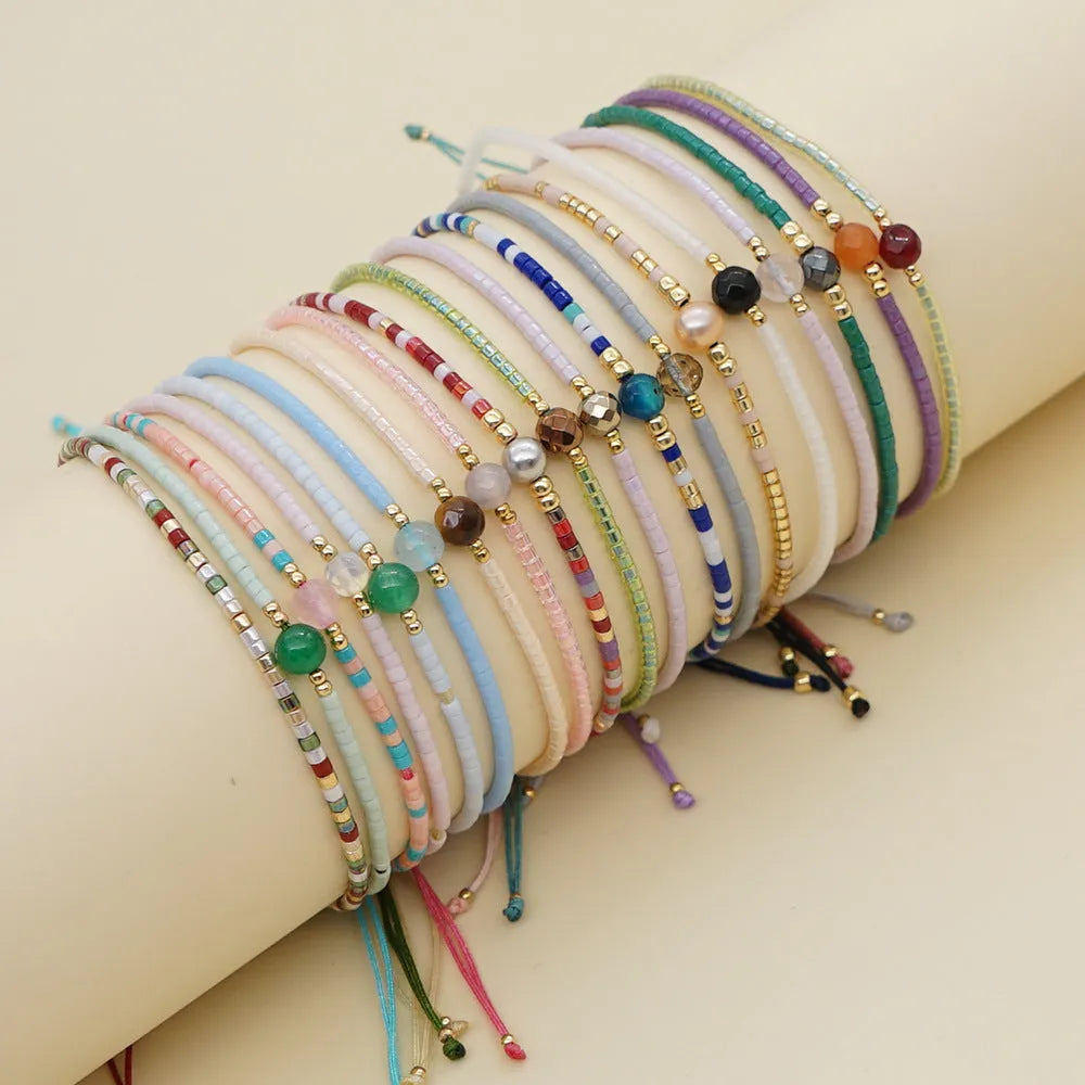 Handmade bohemian style bracelet with geometric semi-precious stone and colourful glass beads on a wrist.