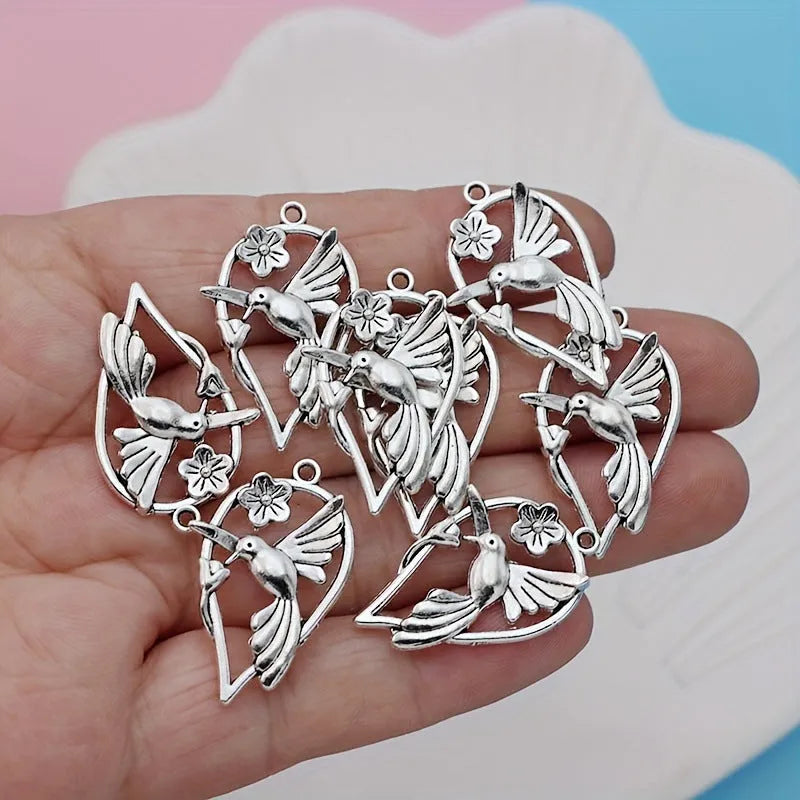 Close-up of a silver-toned alloy magpie bird pendant charm with electroplated finish, shown from the front.