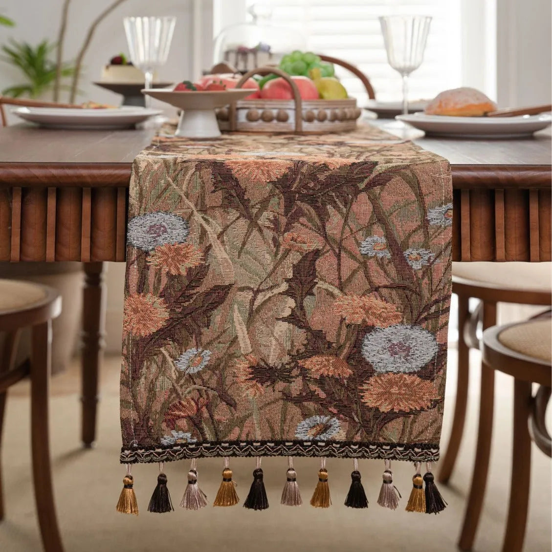 Beige polyester jacquard table runner with long tassels and a floral leaf pattern laid on a table.