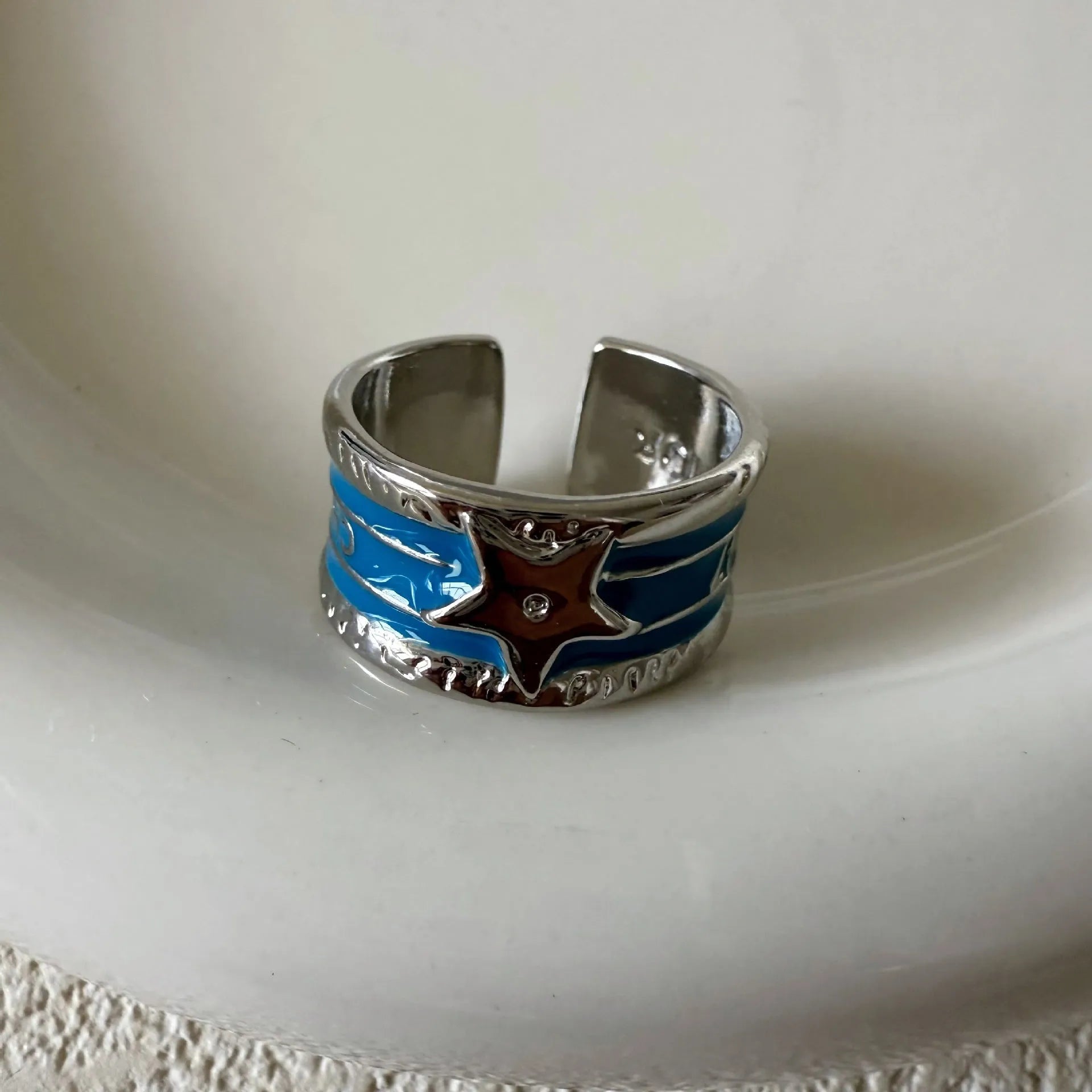 Women's adjustable copper ring with distressed XINGX drop oil design in geometric shape showing colour options