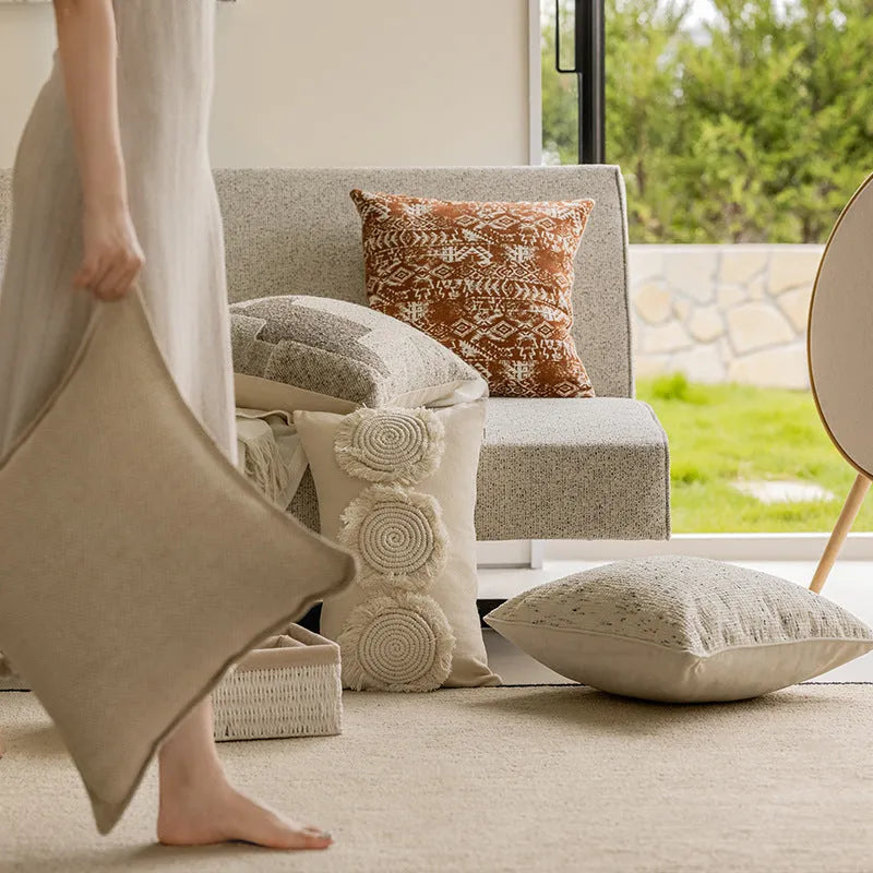A 45cm square solid-colour cushion with stitched edges on a grey sofa.